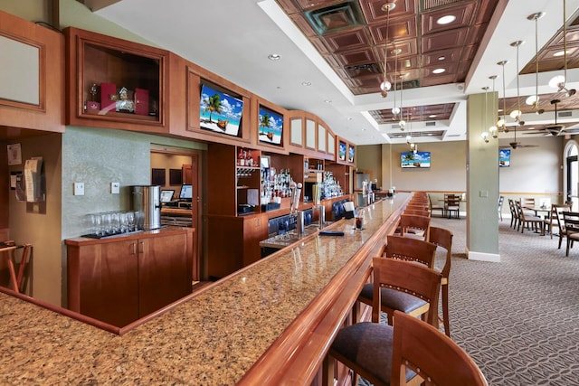 bar with coffered ceiling, light stone countertops, decorative light fixtures, carpet flooring, and ceiling fan