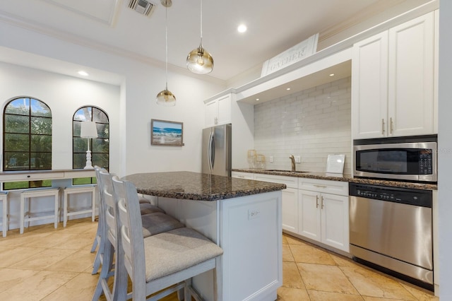 kitchen with appliances with stainless steel finishes, pendant lighting, white cabinets, and dark stone counters