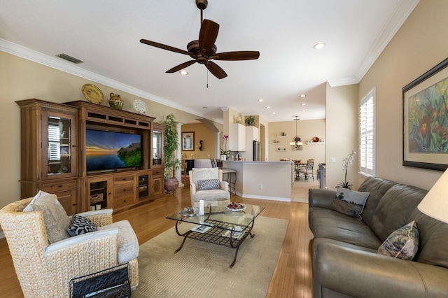 living room featuring ornamental molding, light wood-type flooring, and ceiling fan