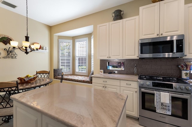 kitchen featuring a kitchen island, stainless steel appliances, pendant lighting, white cabinets, and tasteful backsplash