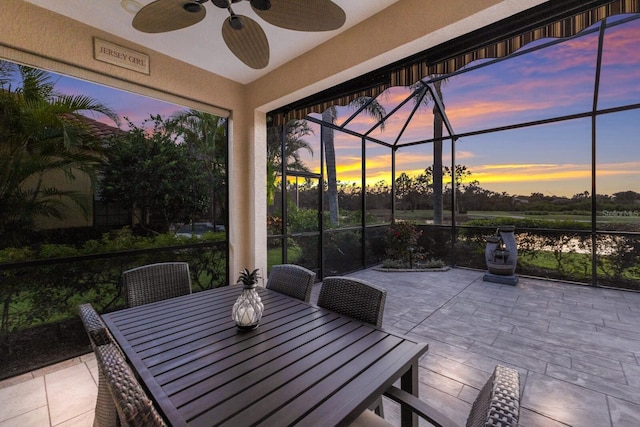 patio terrace at dusk featuring a lanai and ceiling fan