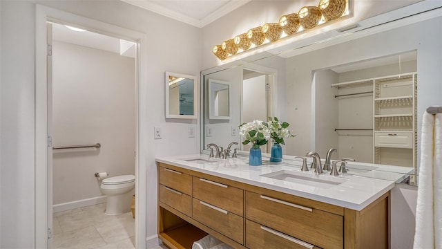 bathroom with double vanity, toilet, a sink, and ornamental molding