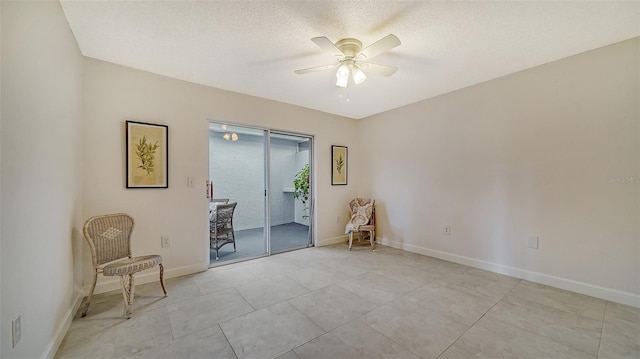 sitting room featuring a ceiling fan, a textured ceiling, and baseboards