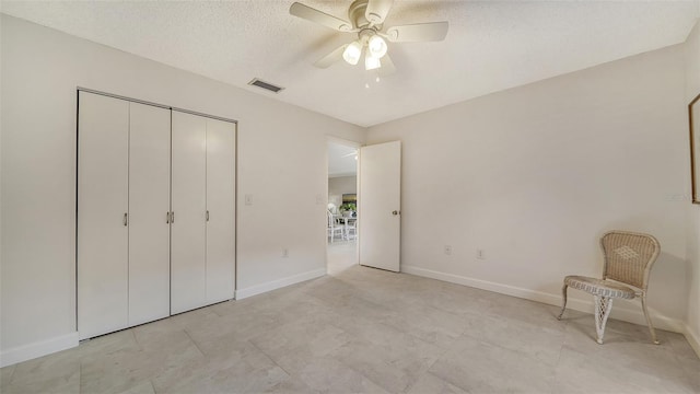 unfurnished bedroom with a textured ceiling, visible vents, baseboards, a ceiling fan, and a closet