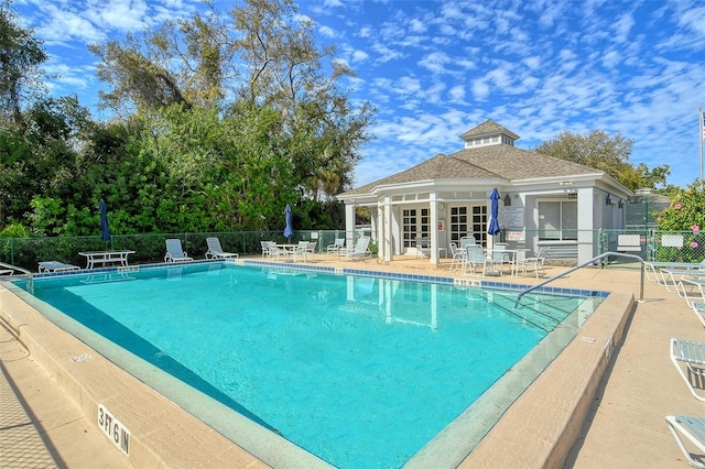 pool featuring fence, an outdoor structure, french doors, and a patio