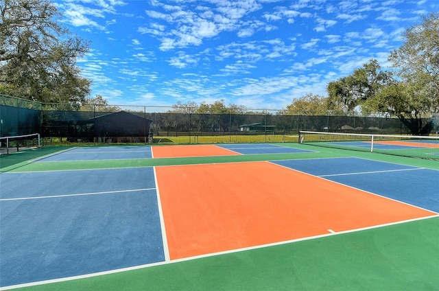 view of tennis court featuring community basketball court and fence