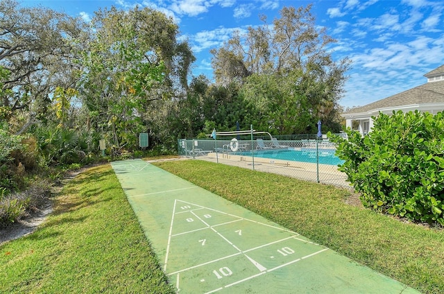 view of home's community with shuffleboard, a lawn, fence, and a pool