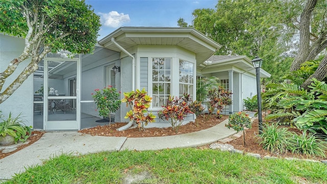 view of property exterior featuring glass enclosure and stucco siding