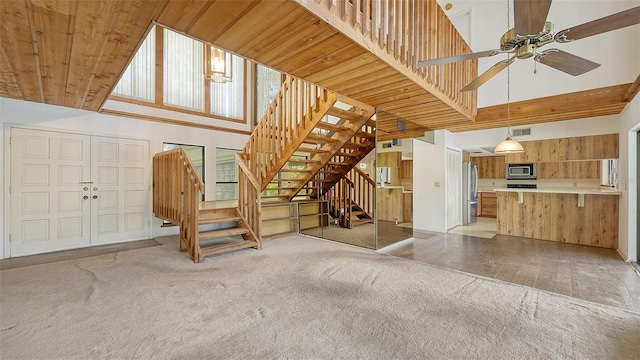 unfurnished living room with wood ceiling, light colored carpet, and a high ceiling