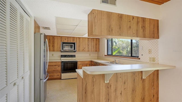 kitchen with kitchen peninsula, backsplash, a breakfast bar area, sink, and stainless steel appliances