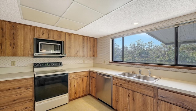 kitchen with sink, stainless steel appliances, a textured ceiling, and tasteful backsplash