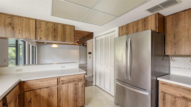 kitchen with decorative backsplash, a textured ceiling, and stainless steel refrigerator