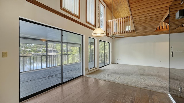 unfurnished room featuring hardwood / wood-style floors, wood ceiling, a high ceiling, and plenty of natural light