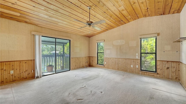 carpeted empty room featuring wood ceiling, wood walls, a healthy amount of sunlight, and lofted ceiling