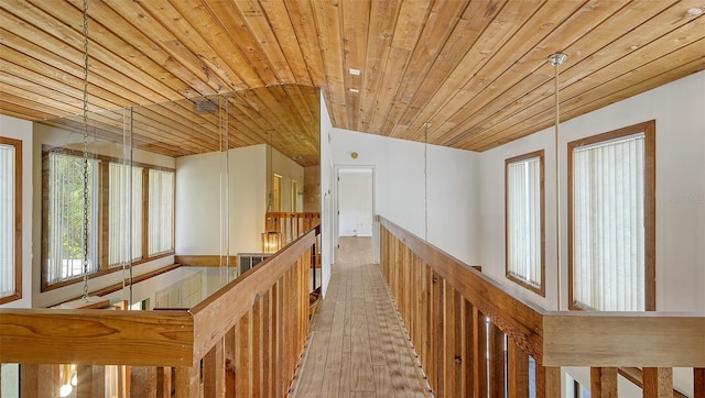 hallway with light hardwood / wood-style floors, wooden ceiling, and lofted ceiling