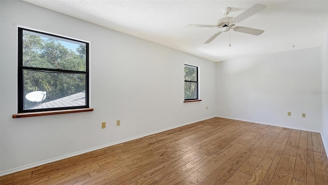 empty room featuring a textured ceiling, light wood-type flooring, and ceiling fan