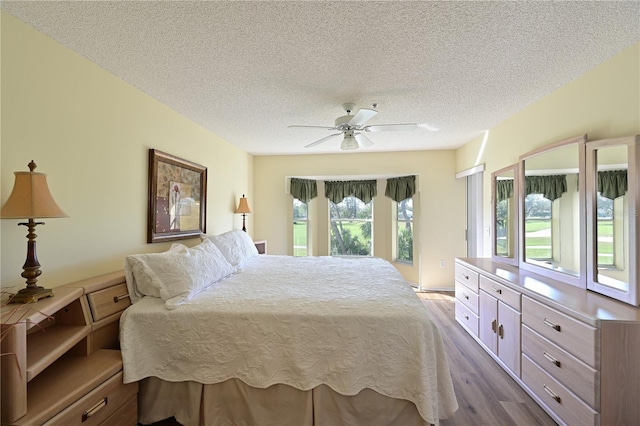 bedroom with ceiling fan, light hardwood / wood-style floors, and a textured ceiling