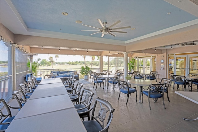 exterior space featuring ornate columns, a tray ceiling, ceiling fan, and french doors