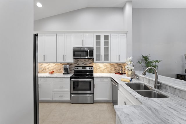 kitchen with sink, stainless steel appliances, tasteful backsplash, white cabinets, and vaulted ceiling