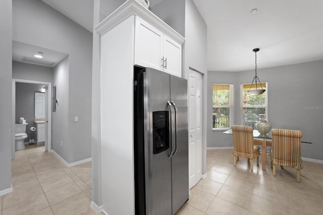 kitchen with stainless steel refrigerator with ice dispenser, white cabinetry, pendant lighting, and light tile patterned floors