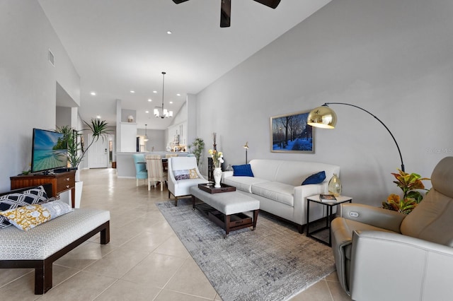 living room with ceiling fan with notable chandelier, high vaulted ceiling, and light tile patterned flooring