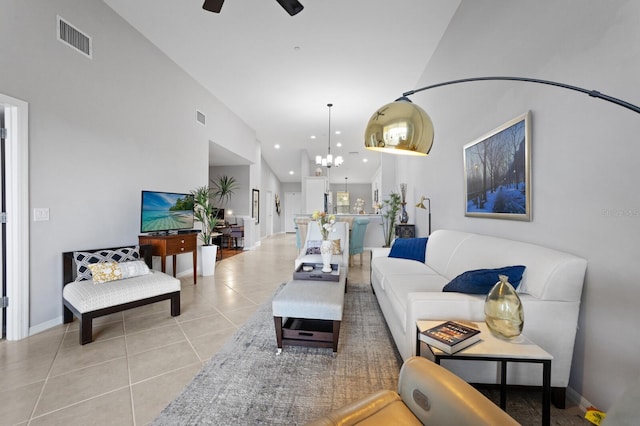 living room with light tile patterned floors, ceiling fan with notable chandelier, and high vaulted ceiling