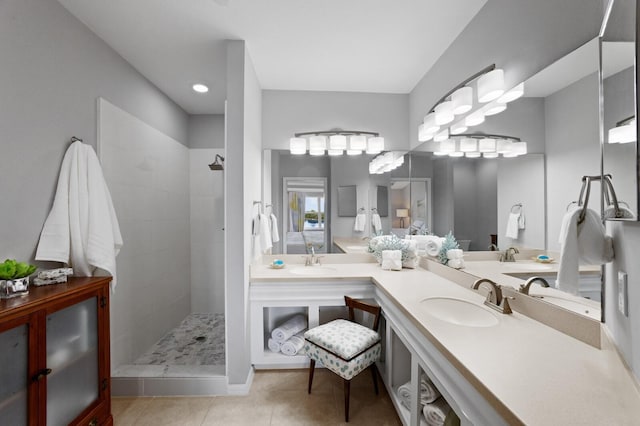 bathroom featuring tile patterned flooring, vanity, and a tile shower