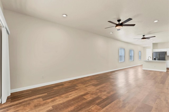 unfurnished living room with hardwood / wood-style flooring, sink, and ceiling fan