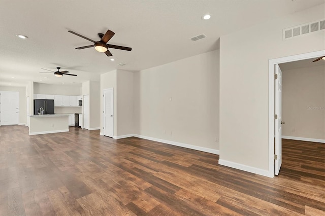 unfurnished living room featuring ceiling fan and dark hardwood / wood-style flooring