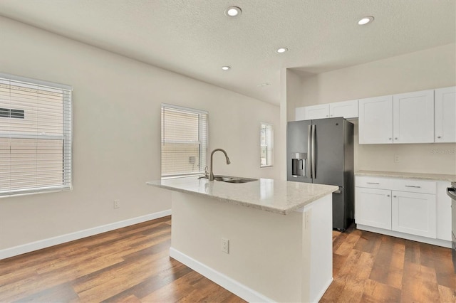 kitchen featuring sink, stainless steel fridge with ice dispenser, an island with sink, and white cabinets