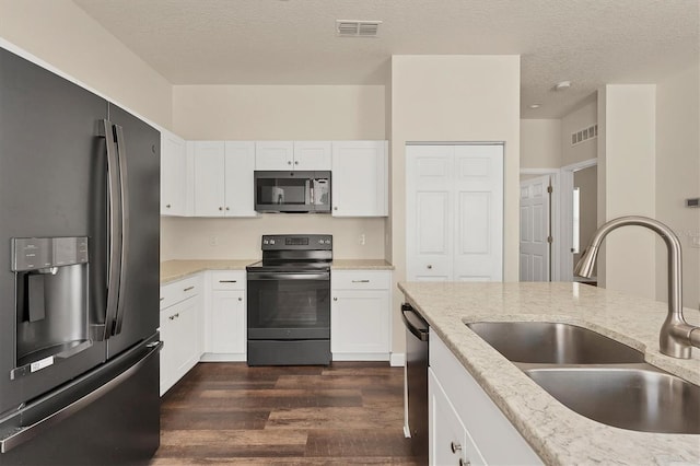 kitchen with dark wood-type flooring, sink, white cabinetry, appliances with stainless steel finishes, and a textured ceiling