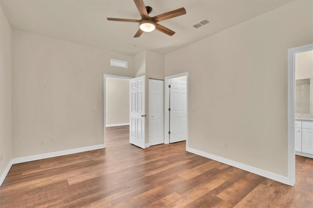 unfurnished bedroom featuring hardwood / wood-style floors, ensuite bath, and ceiling fan