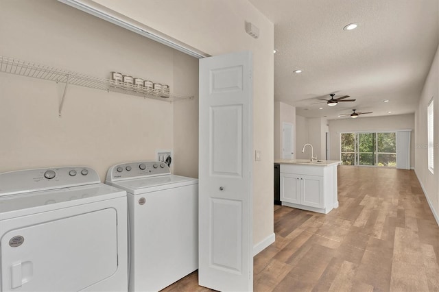 washroom with ceiling fan, washer and dryer, a textured ceiling, light hardwood / wood-style floors, and sink