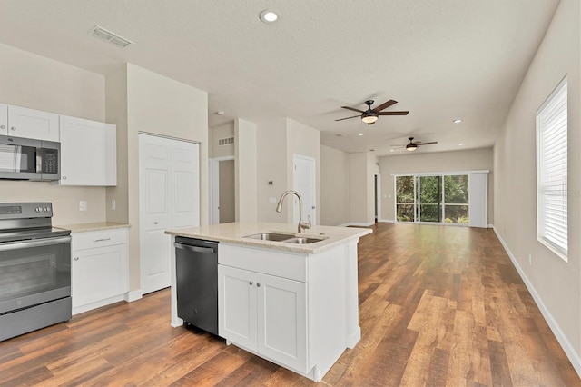 kitchen with hardwood / wood-style floors, sink, appliances with stainless steel finishes, and white cabinetry