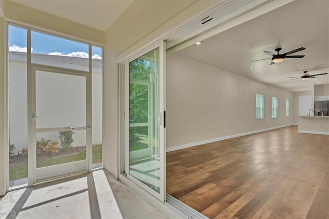 unfurnished sunroom with ceiling fan