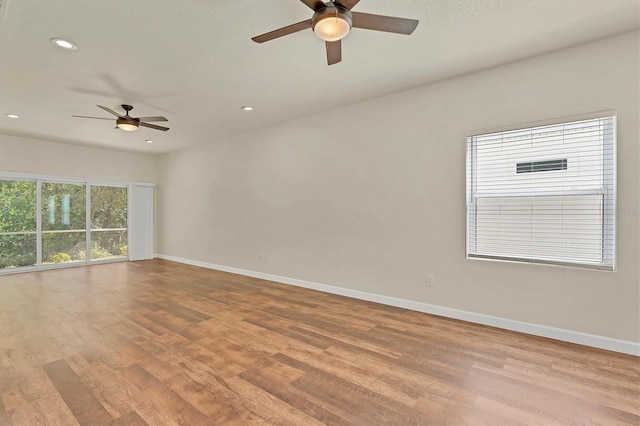 spare room with recessed lighting, baseboards, a textured ceiling, and light wood finished floors