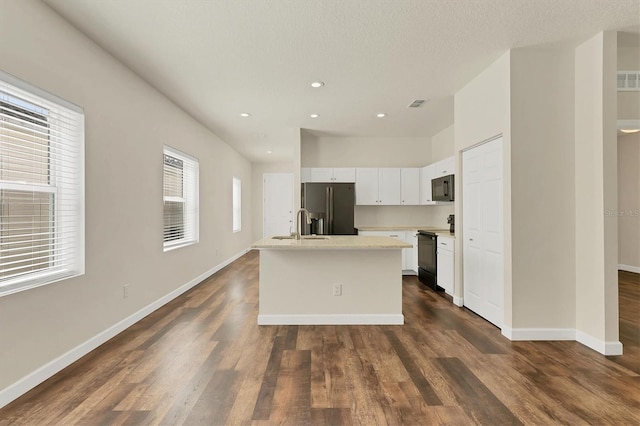 kitchen with a kitchen island with sink, white cabinets, light countertops, dark wood-style floors, and black appliances