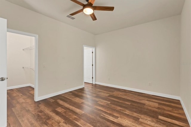 unfurnished room featuring dark wood-style floors, visible vents, and baseboards