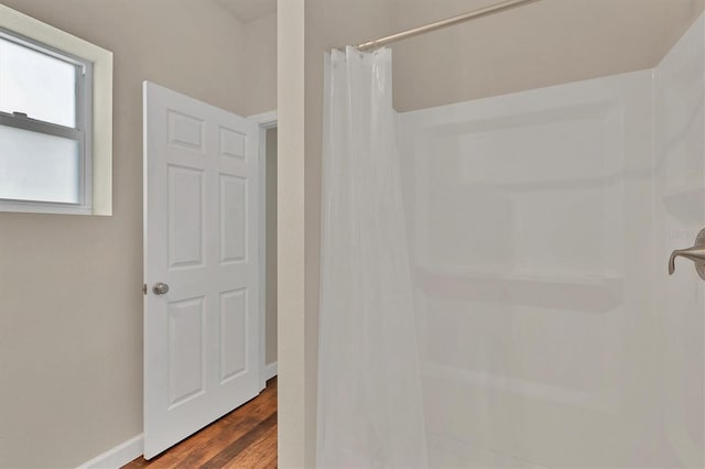 full bathroom featuring curtained shower, baseboards, and wood finished floors