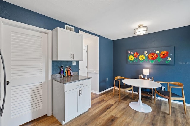 kitchen featuring decorative backsplash, white cabinets, dark stone countertops, and wood-type flooring