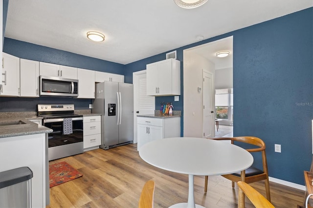 kitchen featuring appliances with stainless steel finishes, sink, light wood-type flooring, and white cabinets