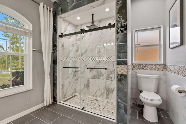 bathroom featuring toilet, a shower with door, and a wealth of natural light