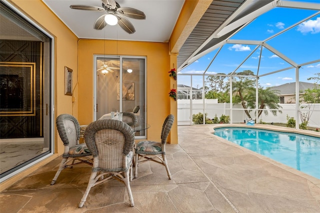 view of swimming pool featuring glass enclosure, a patio area, and ceiling fan