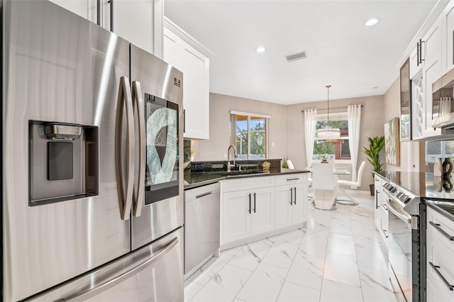 kitchen featuring sink, dark stone countertops, decorative light fixtures, white cabinetry, and stainless steel appliances