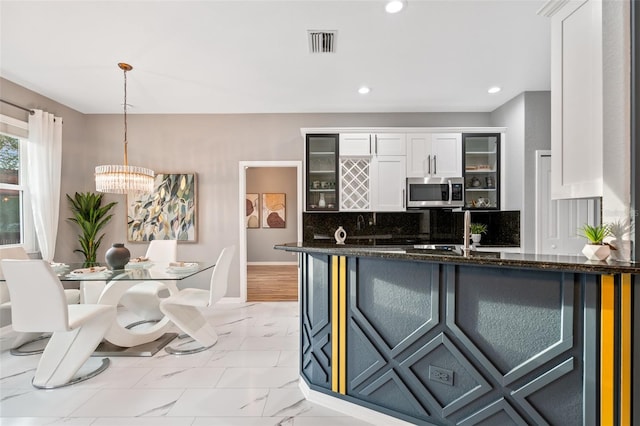 kitchen featuring tasteful backsplash, sink, decorative light fixtures, dark stone countertops, and white cabinets