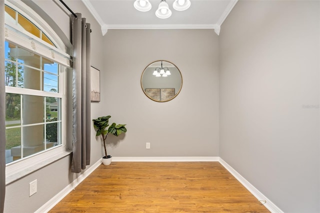 spare room featuring light hardwood / wood-style flooring, an inviting chandelier, plenty of natural light, and ornamental molding