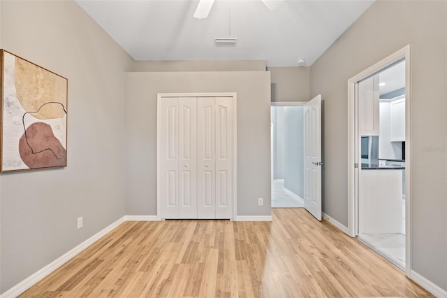 unfurnished bedroom featuring ceiling fan, a closet, and light hardwood / wood-style flooring