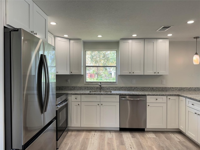 kitchen with white cabinetry, light hardwood / wood-style floors, stainless steel appliances, and sink