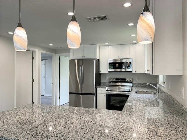 kitchen with white cabinets, light stone counters, appliances with stainless steel finishes, sink, and decorative light fixtures