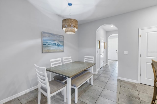 dining area featuring light tile patterned floors, baseboards, arched walkways, and an inviting chandelier